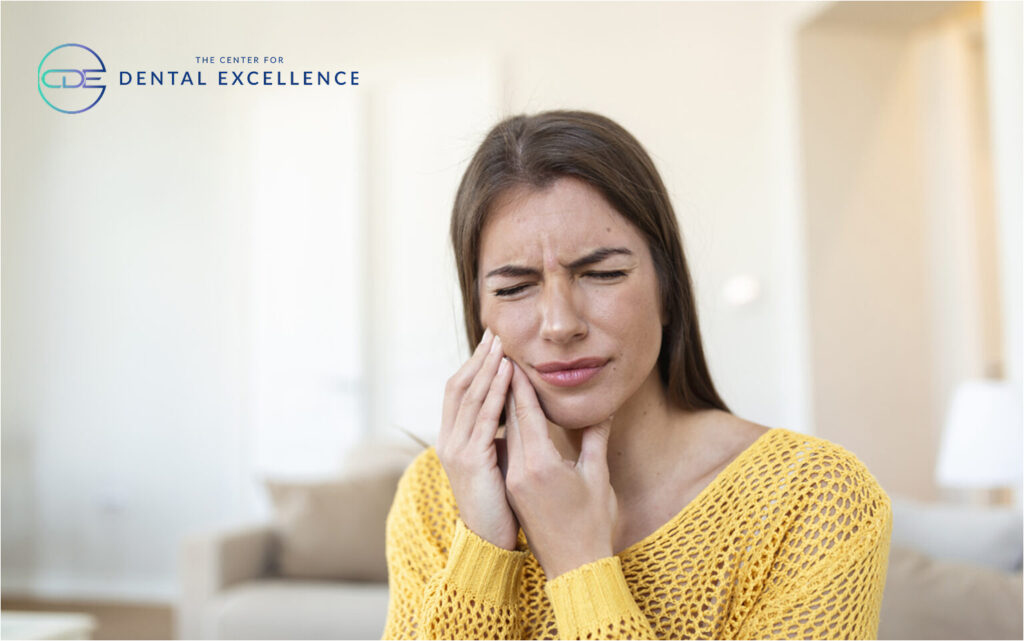 Woman holding her cheek in pain, suffering from a toothache.